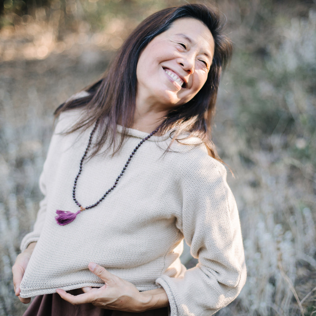 Joyous Asian woman Wearing Sakti Rising Bagala Crop Sweater in Oat, sustainable and ethical yoga meditation apparel.