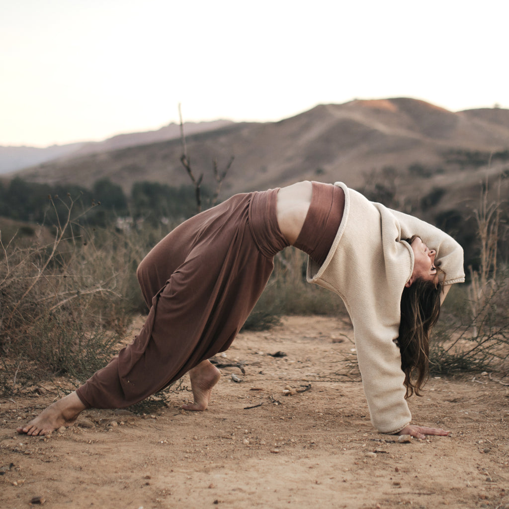 Woman practicing yoga on a mountainside. Wearing Sakti Rising Bagala Crop Sweater in Oat, sustainable and ethical yoga meditation apparel