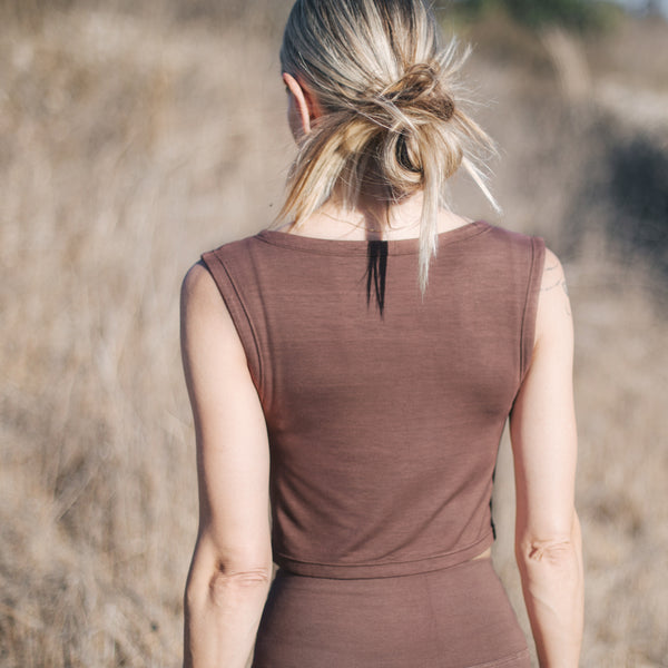 Back of blond woman's torso, wearing Sakti Rising Tara Tank in Cacao. Ethical, sustainable yoga apparel.
