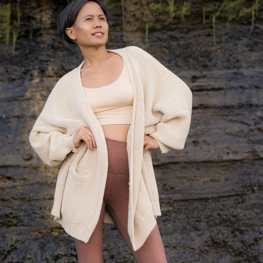 Sakti Rising Dhumavati in Oat, ethical sustainable yoga apparel. Woman standing in confident pose wearing a cozy sweater cardigan