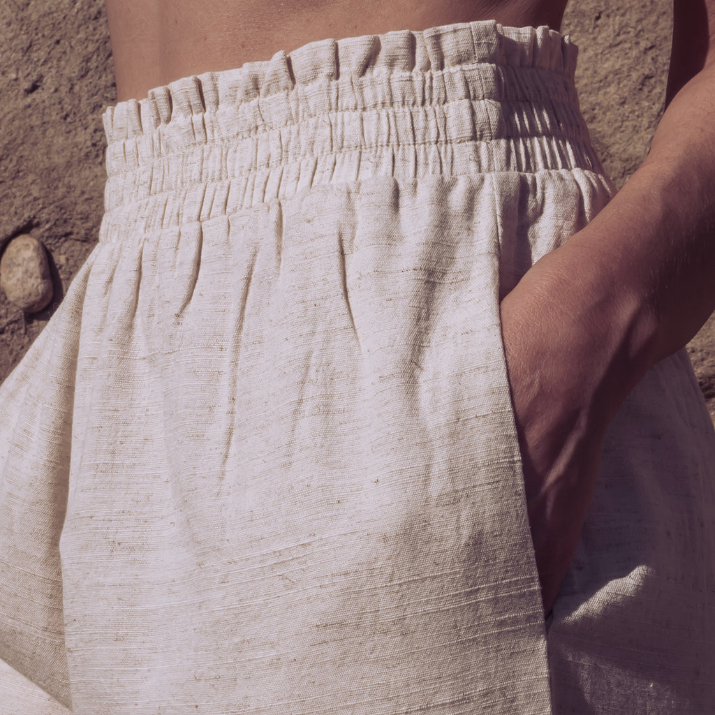 Detail of Sakti Rising Durga Pants ruched waistline, with hand in pocket. Ecofriendly sustainable yoga apparel that gives back to marginalized communities around the world.