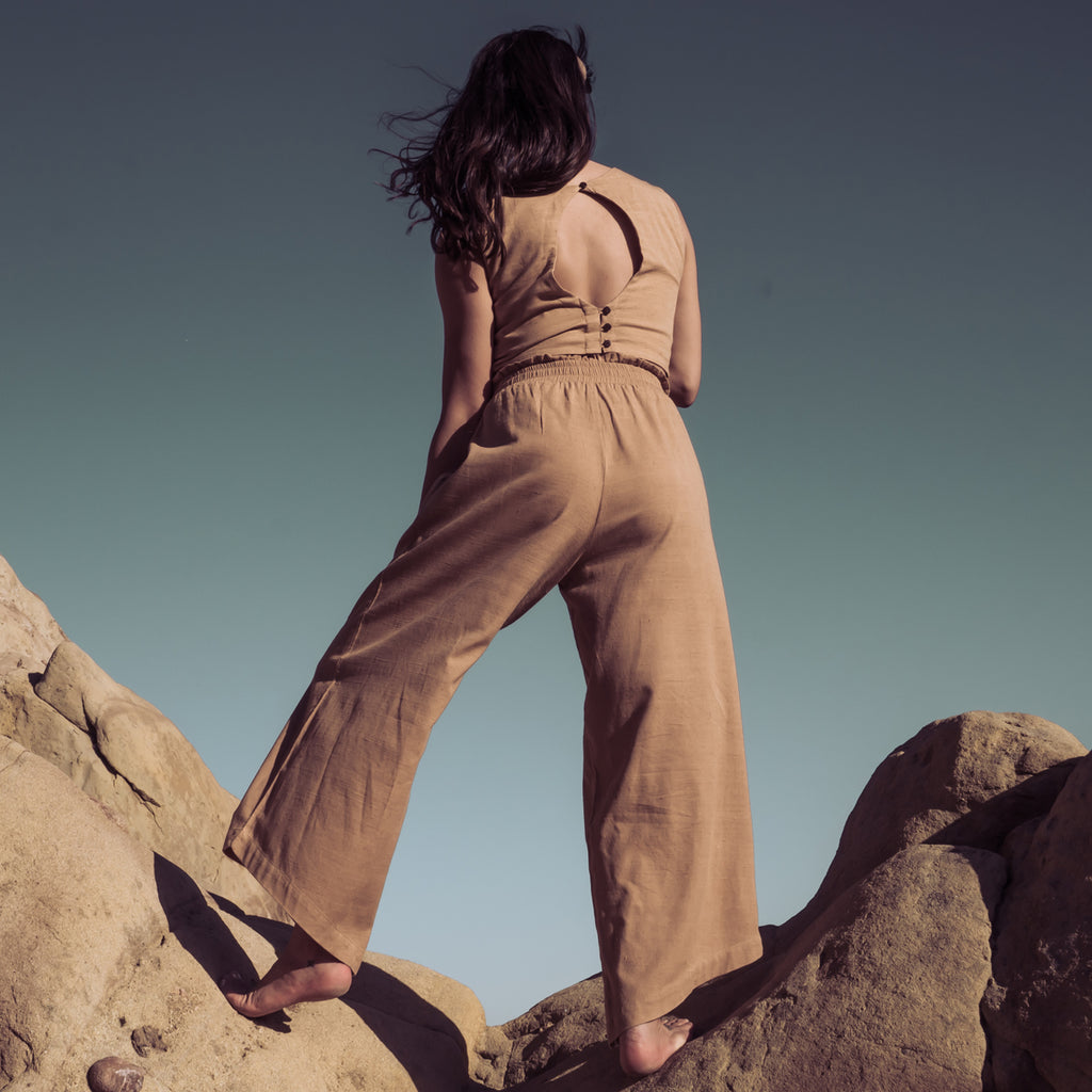 Back view of woman standing on mountaintop wearing Sakti Rising Durga Pants and Radha Crop Top. Ecofriendly sustainable yoga apparel that gives back to marginalized communities around the world.
