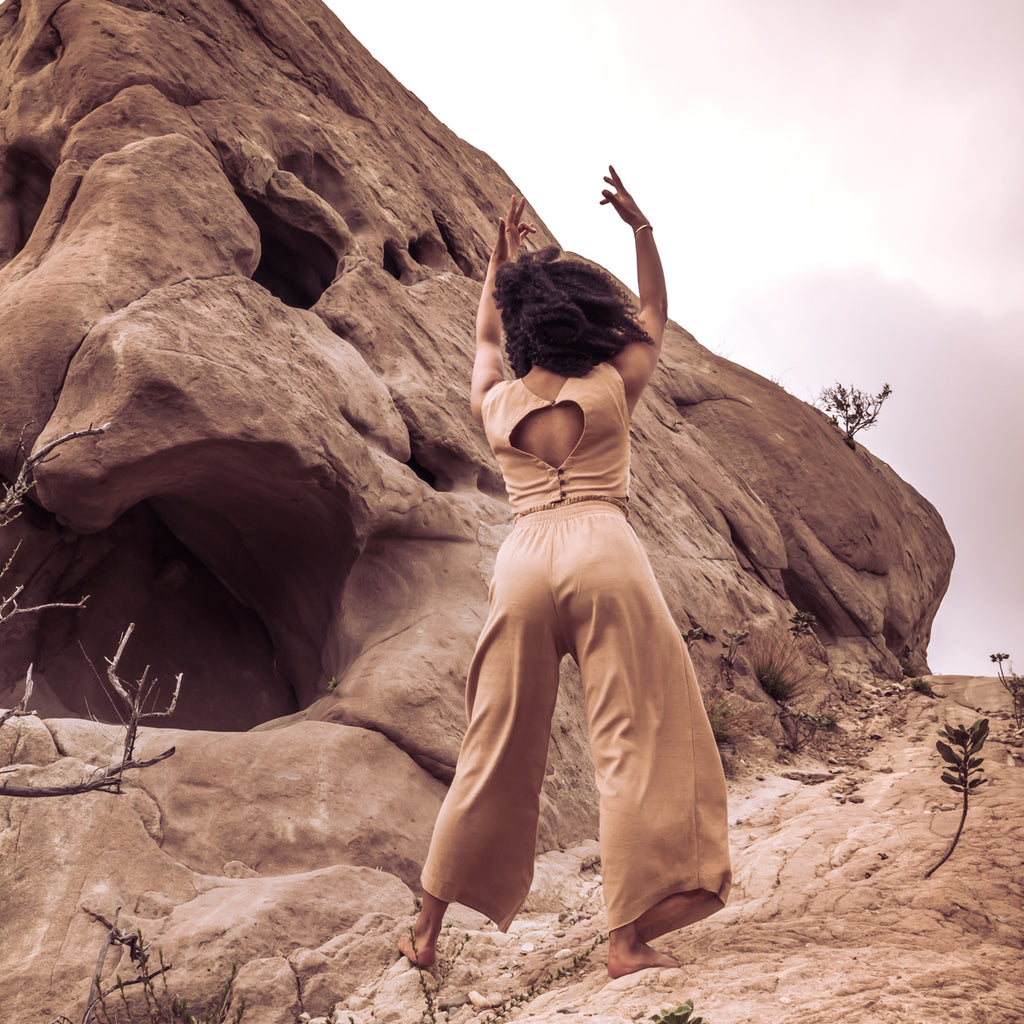 Woman standing on mountain wearing Sakti Rising Durga Pants and Radha Crop Top. Ecofriendly sustainable yoga apparel that gives back to marginalized communities around the world.