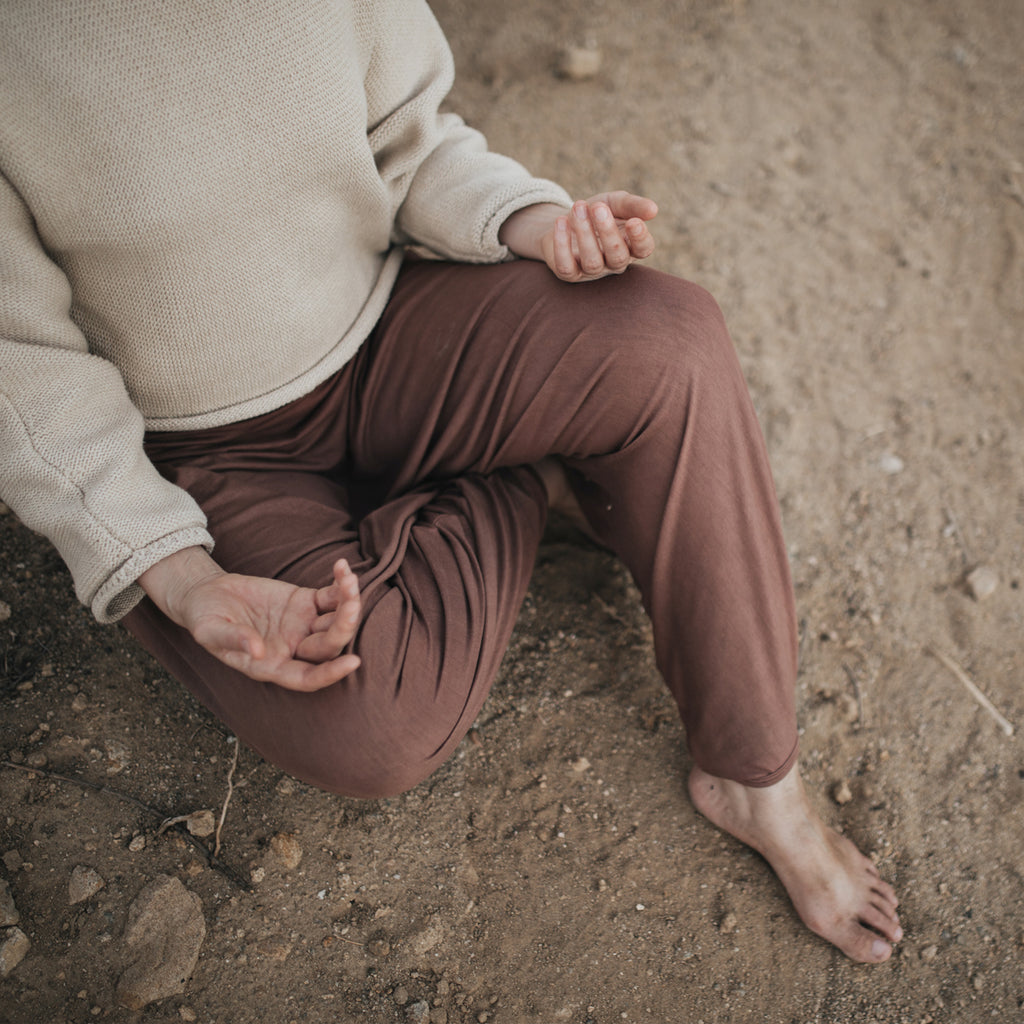 Woman's body in meditation pose, wearing Sakti Rising Parvati Pants in Cacao. Ethical, Sustainable yoga apparel.