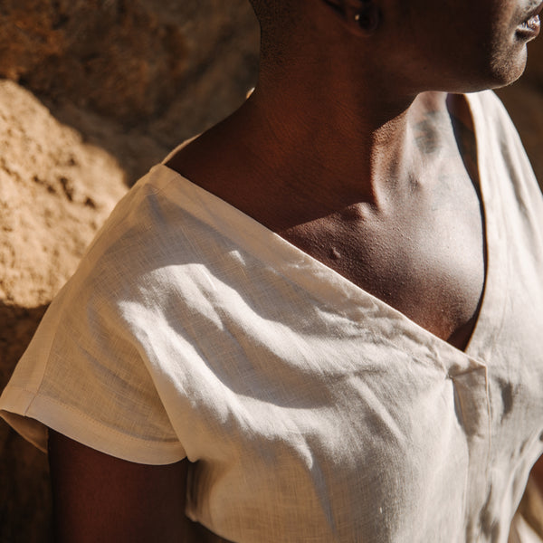 Closeup of Black woman's neckline, wearing Sakti Rising Sita Tunic in Pearl. Ethical sustainable yoga apparel. 