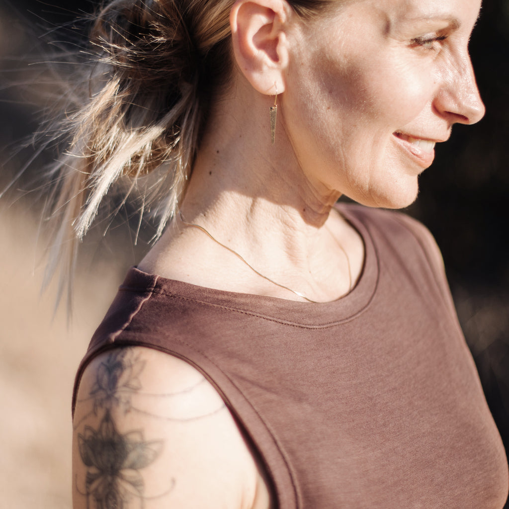 Closeup of smiling caucasian woman's profile, wearing Sakti Rising Tara Tank in Cacao. Ethical, sustainable yoga apparel.